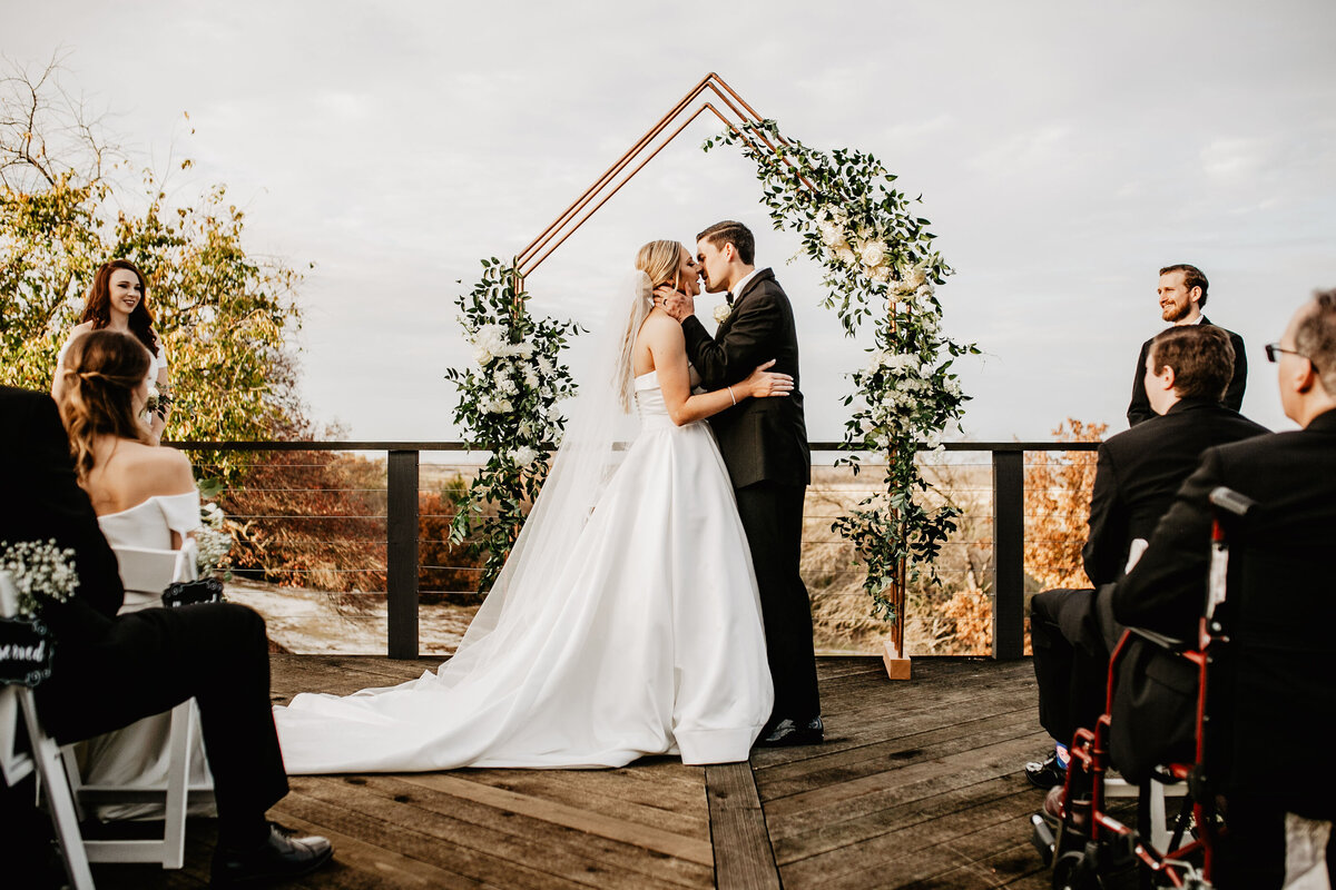 bride and groom kissing under arch