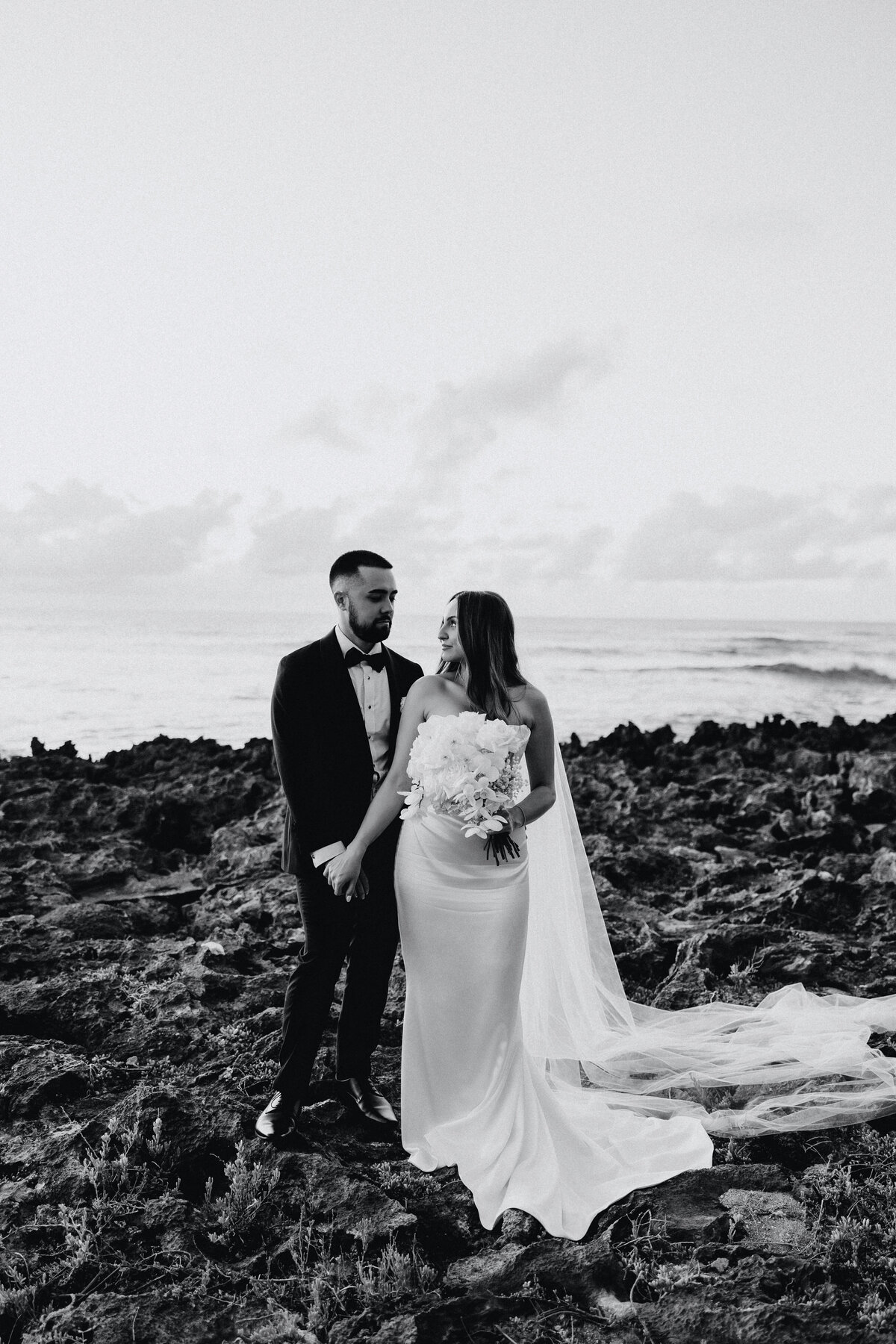 Wedding photography, bride and groom couples portrait on the rocks holding hands in black and white