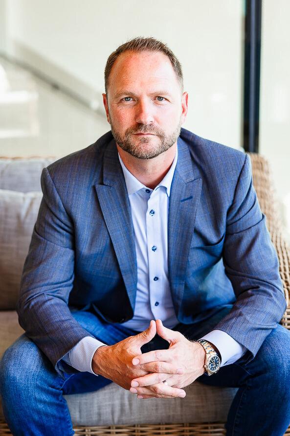 Man in blue suit leans forward on couch as a part of his branding session.
