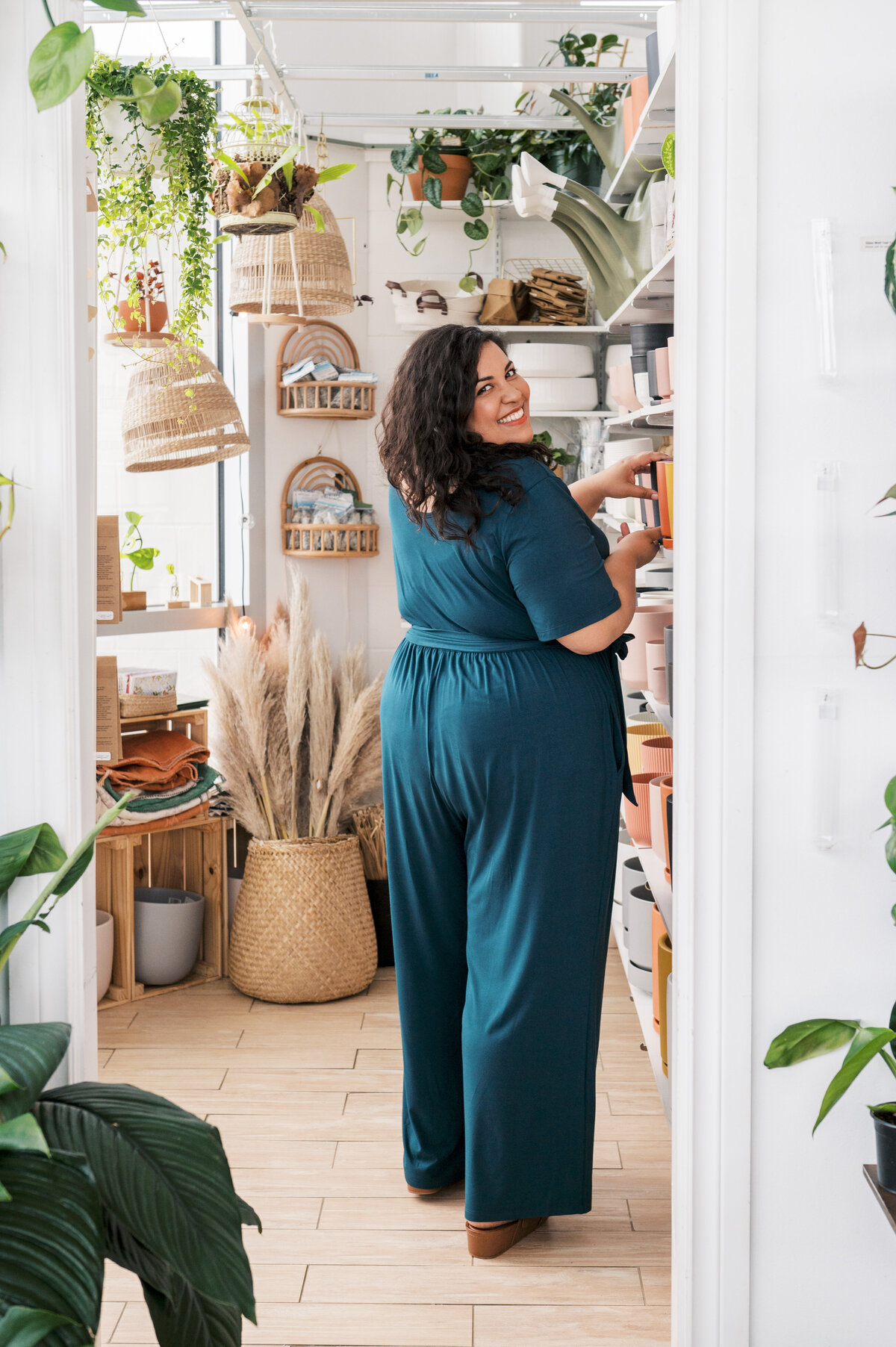 Woman wearing blue jumpsuit looking over her shoulder in plant store
