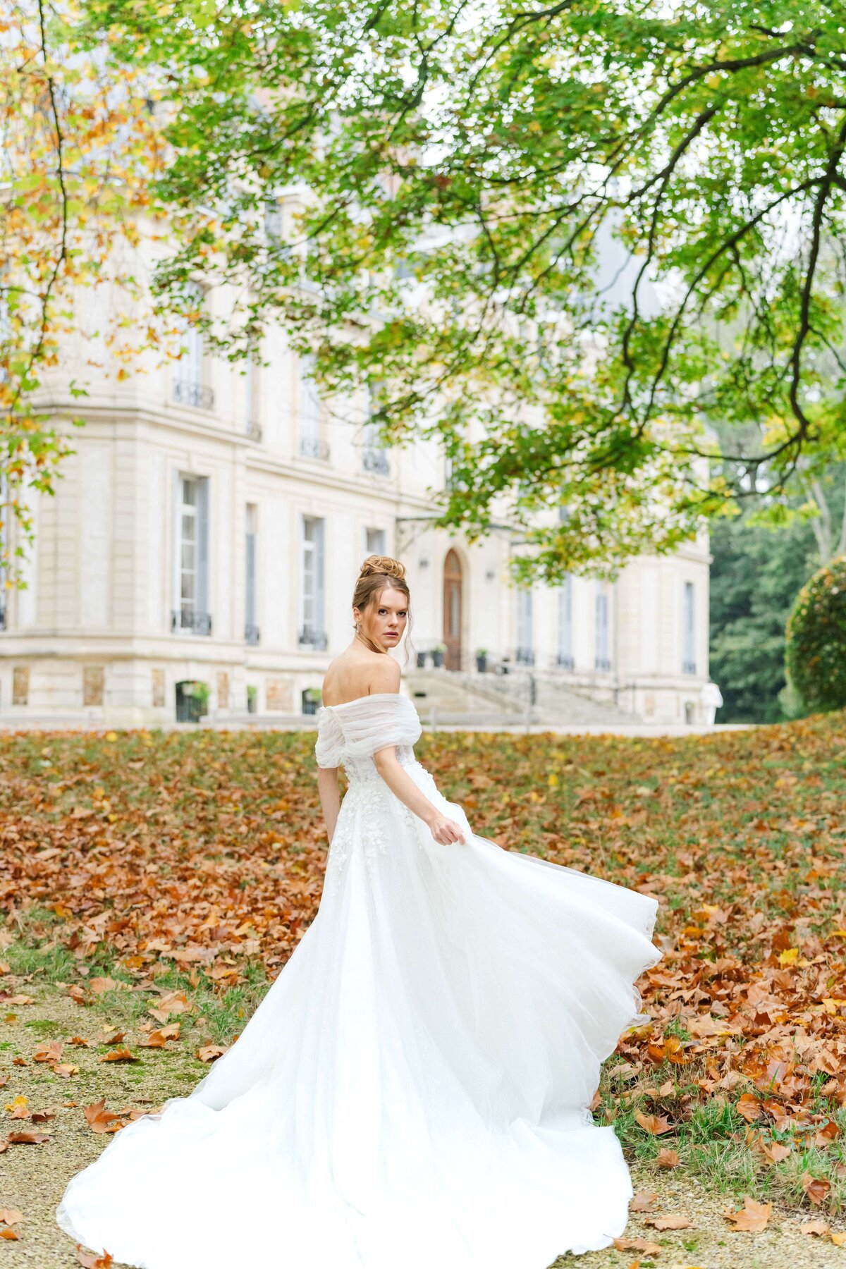 bride on her dress with atum leaves on the backgrond, she si looking at the camera