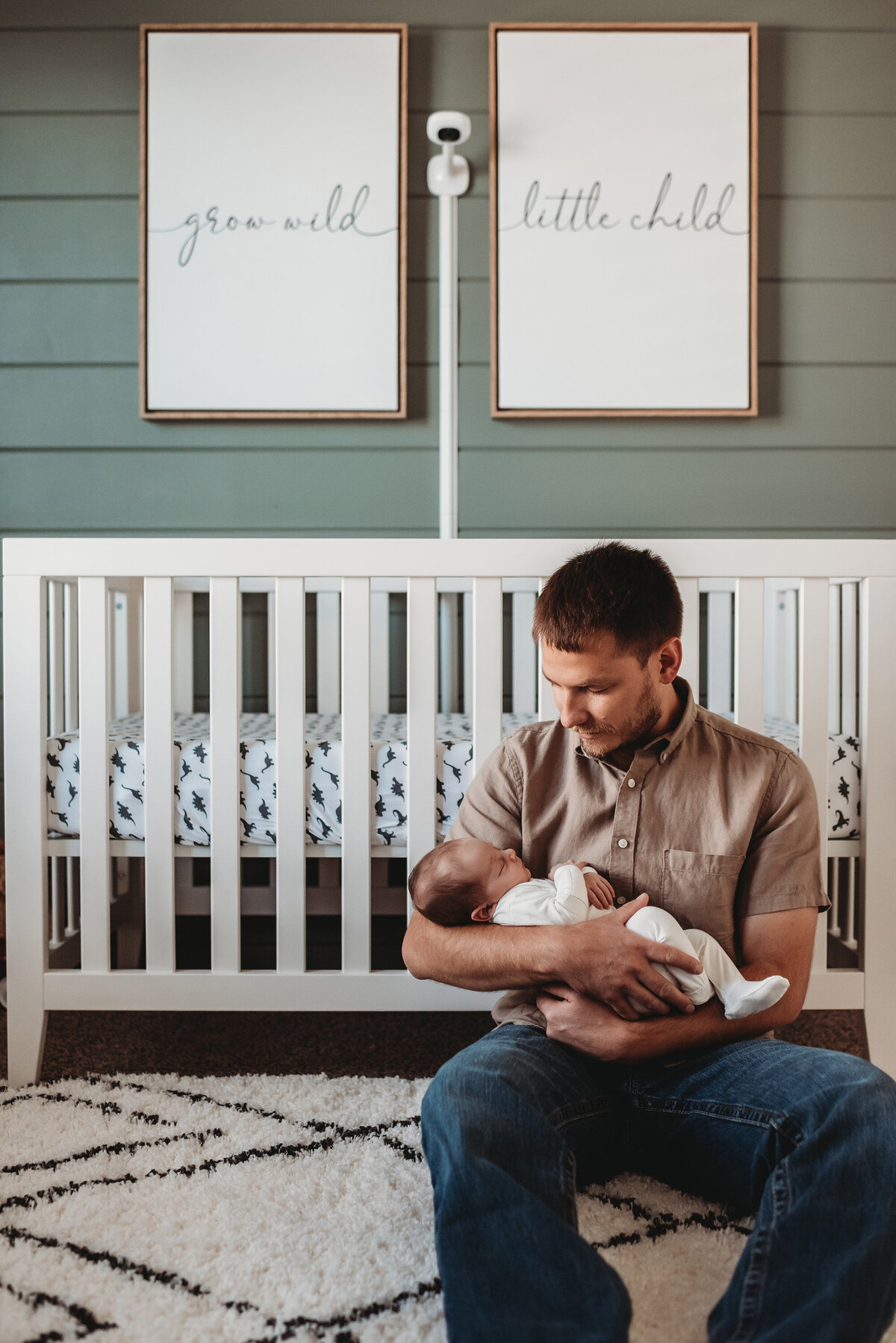 father holding baby boy in front of his crib