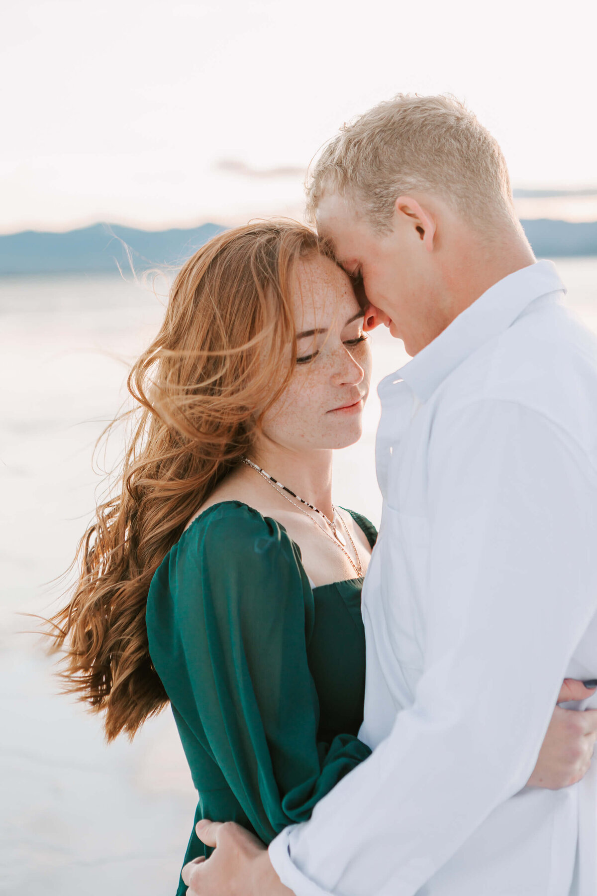 An engaged couple stands together  hugging