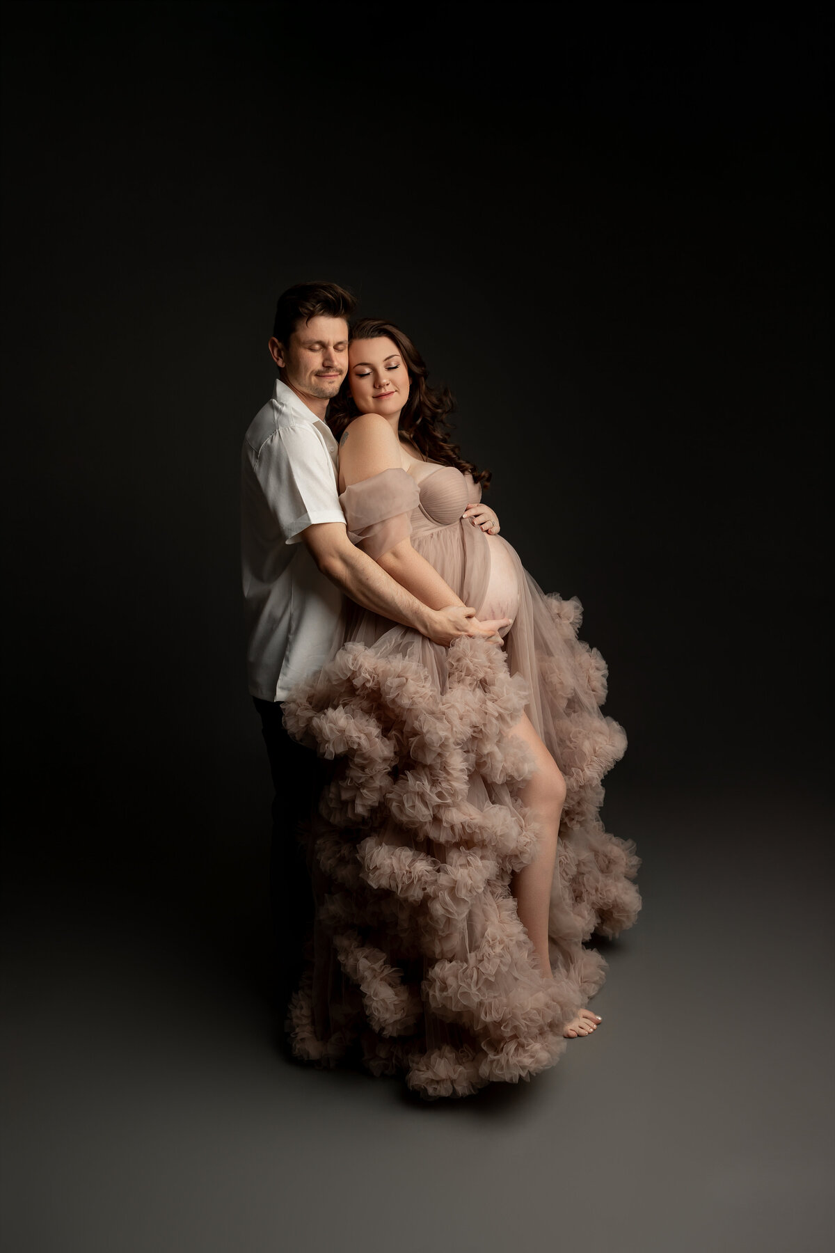 The mother-to-be stands beside her husband, both sharing a quiet moment, their love and excitement shining as they await their baby’s arrival. Captured by Inland Empire maternity photographer Kaitlyn Dawn Photography.