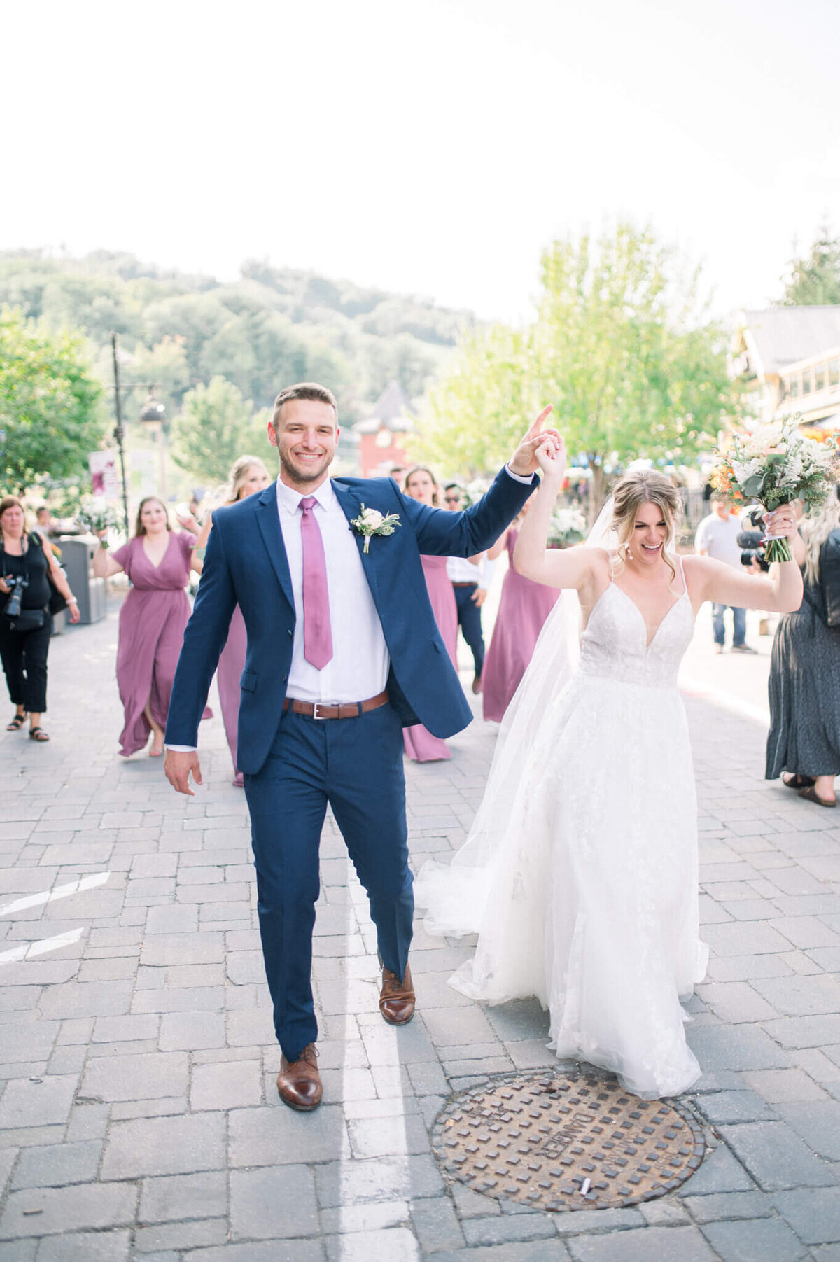 Bride and groom walking down path with arms held high captured by Niagara wedding photographer