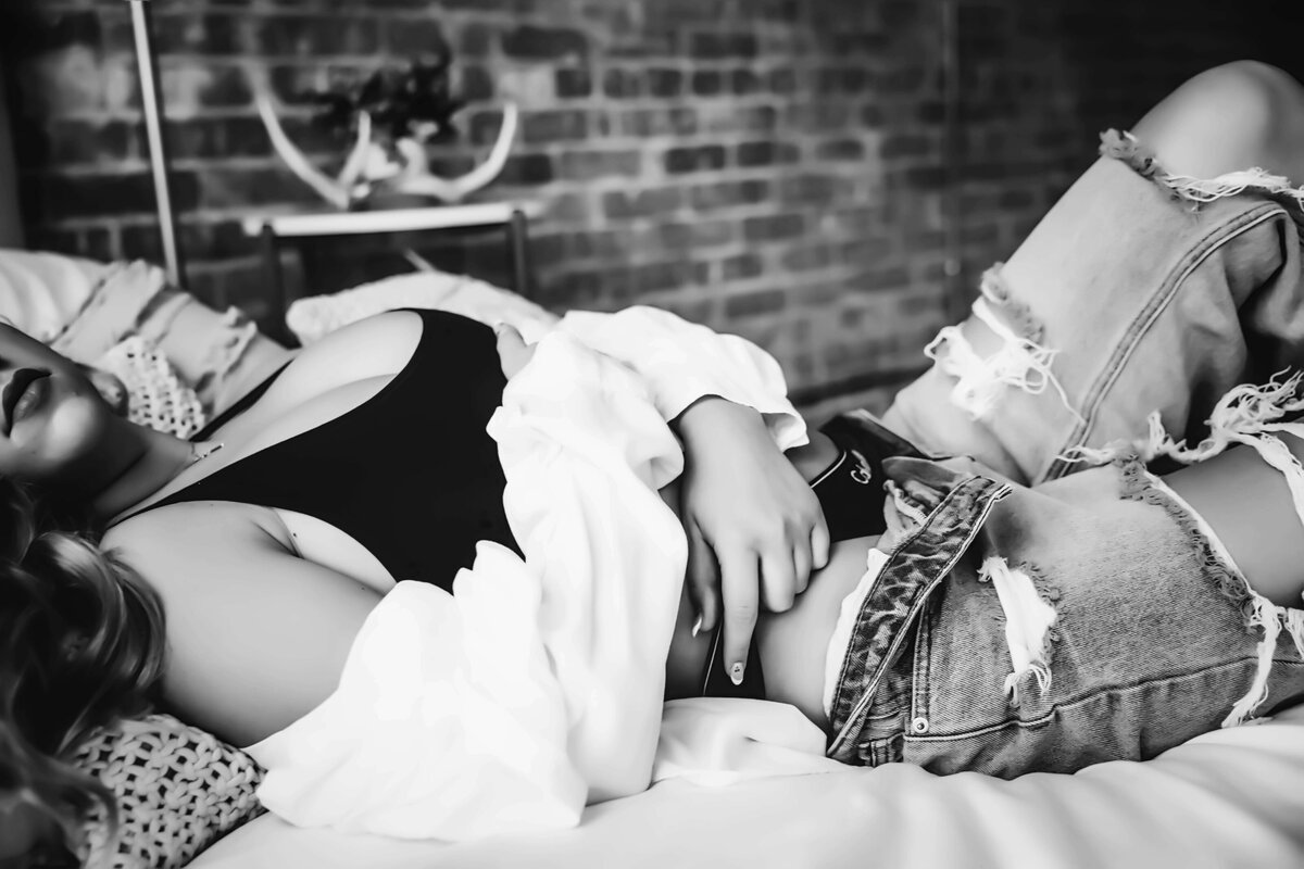 Woman laying on bed in Calvin Klein and jeans for boudoir session with Reva Davis photography
