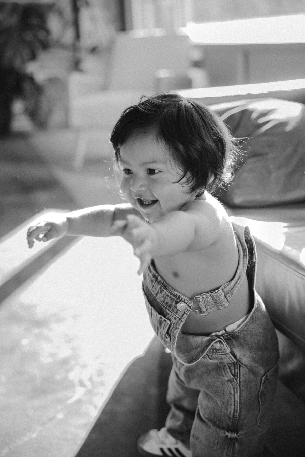 Black and White Candid Baby Portrait Laughing in Denim Overalls Indoors