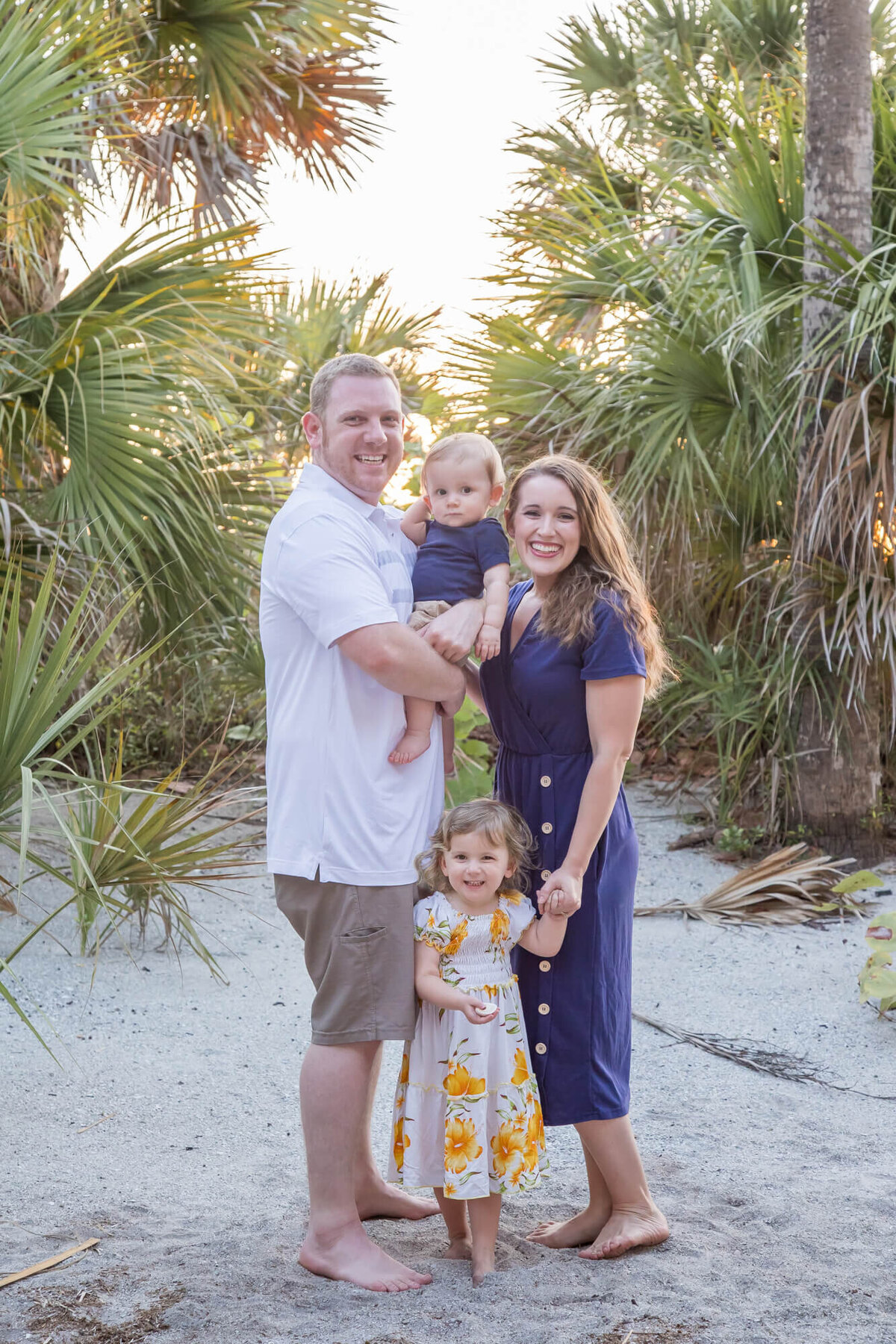 A couple with their two toddlers standing by palm trees