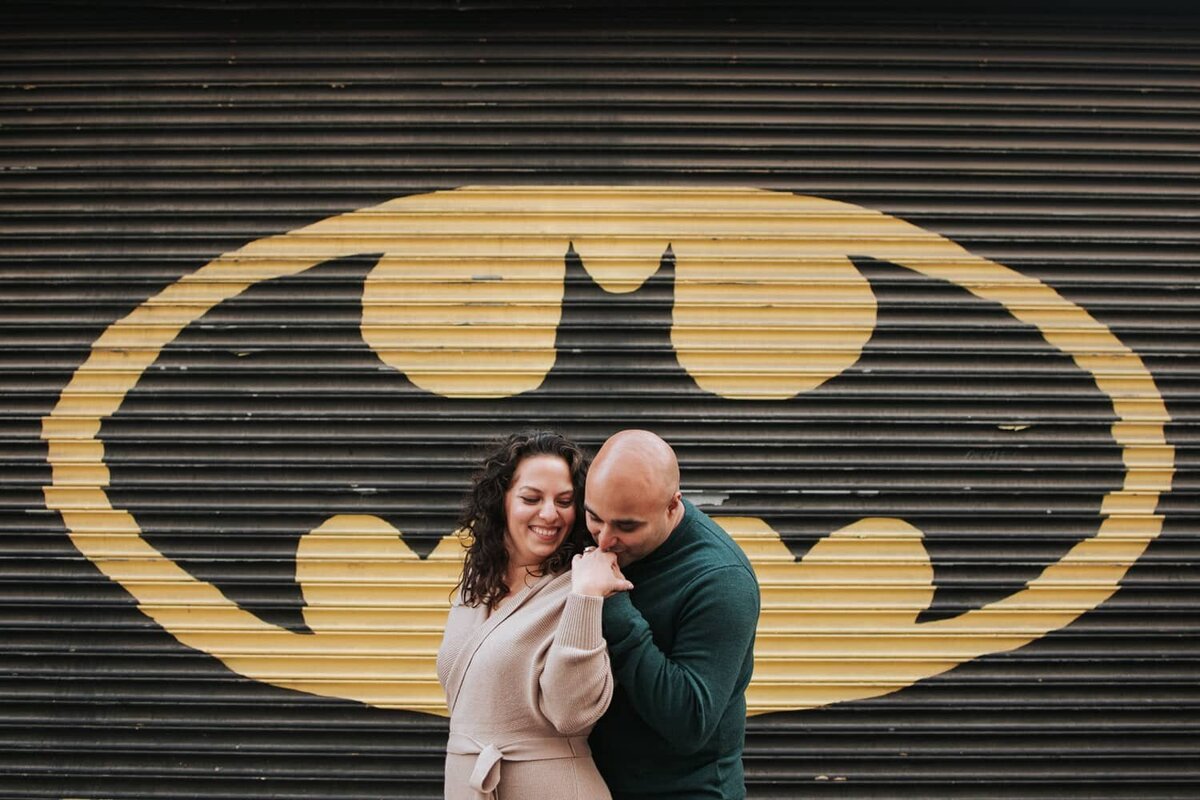 Couple embracing a moment of solitude in front of a batman mural in Philadelphia.