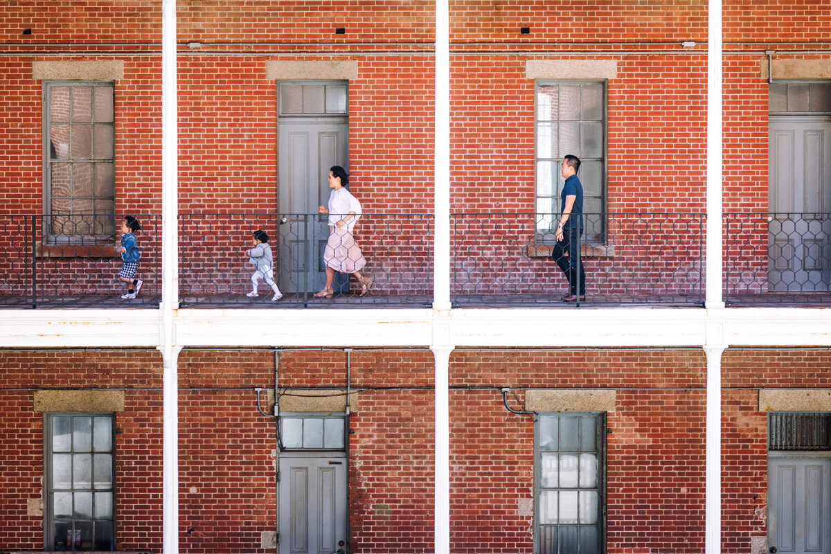 mom and dad and two young children running along outdoor hallway at Fort Point in San Francisco