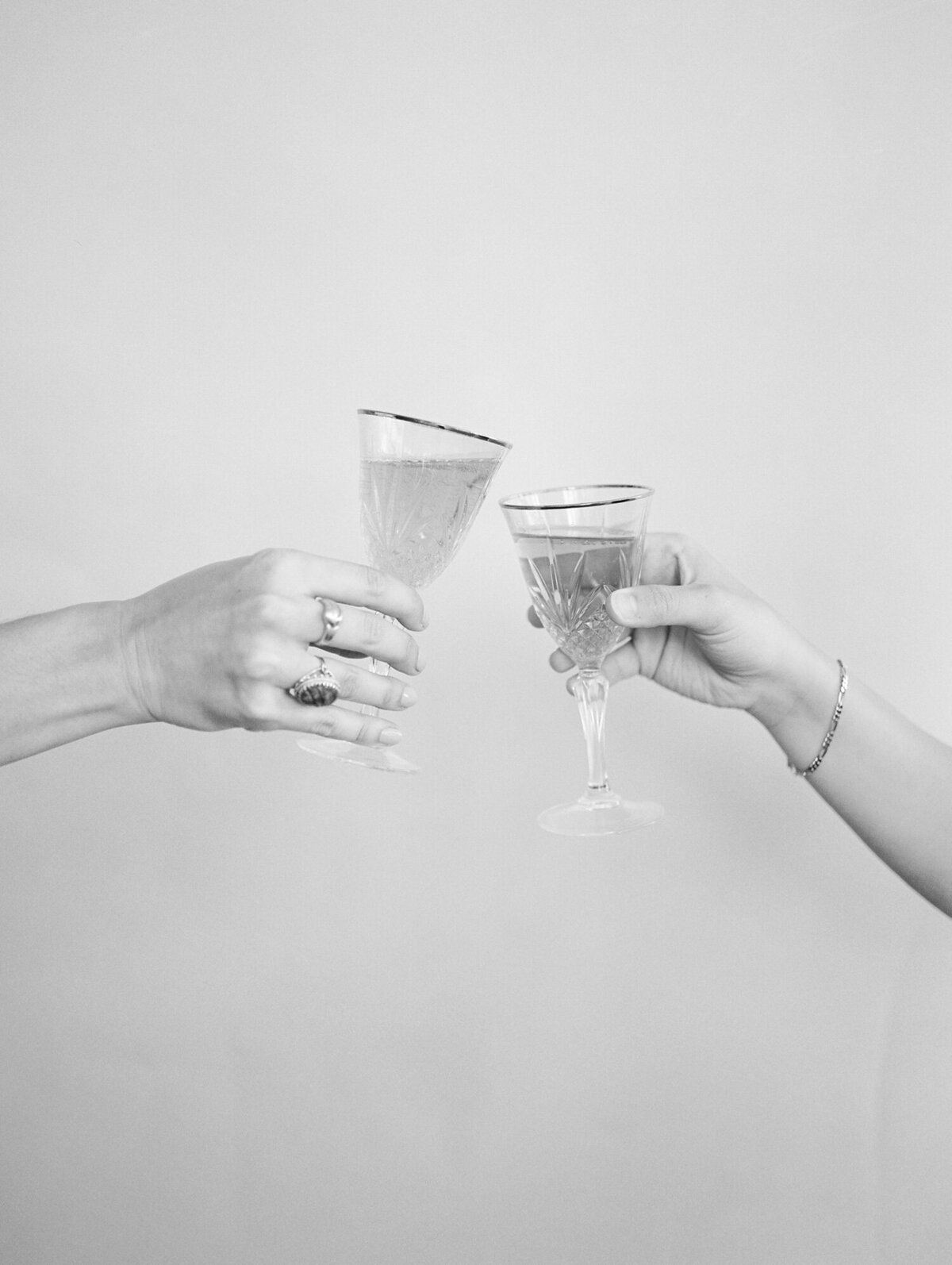 two female hands cheers with champagne, ornate vintage glasses