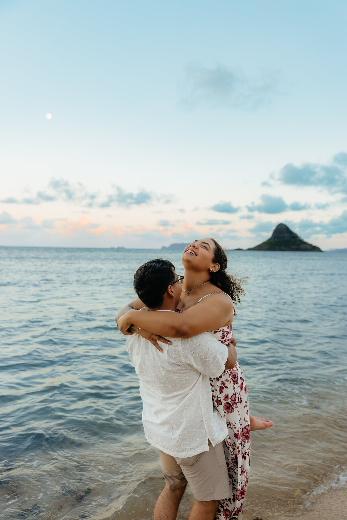Couple dancing around and laughing together during sunset photoshoot at Kualoa Beach in Hawaii