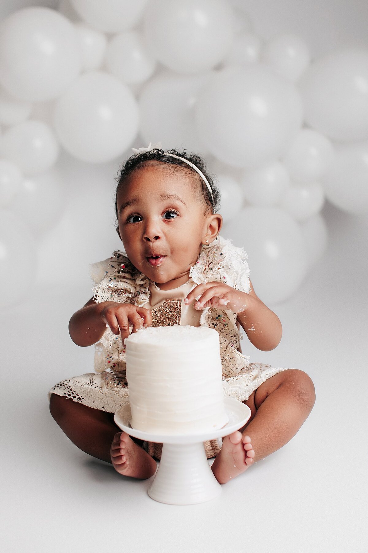 First birthday cake smash setup with balloons and pastel decorations