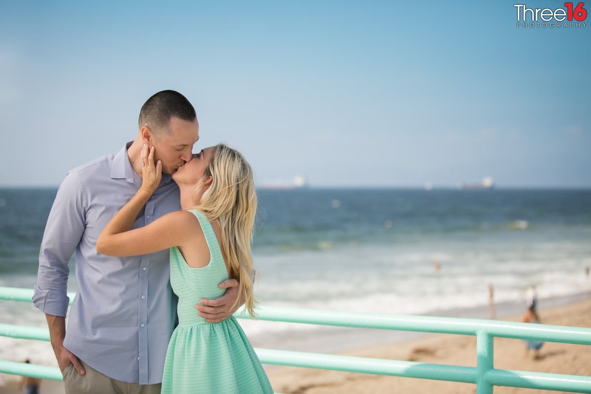 Engaged couple share a romantic kiss on the Manhattan Beach Pier