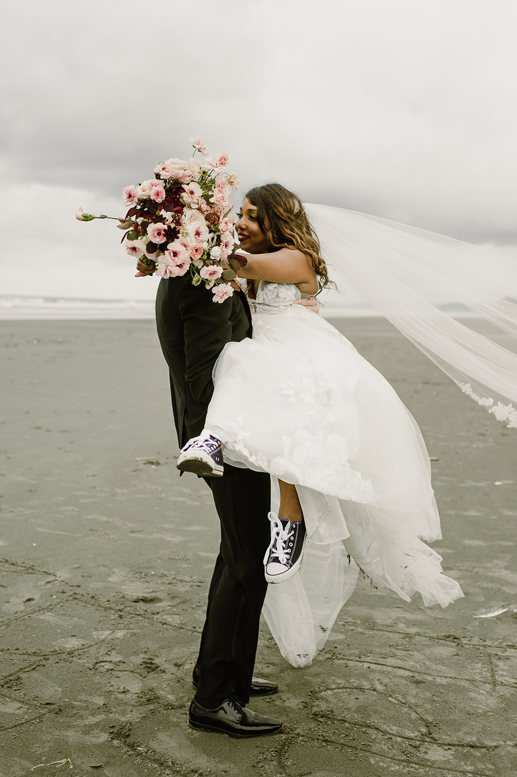 Groom carrying bride along Kalaloch Beach after their Olympic National Park elopement!