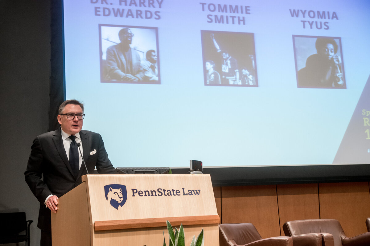 a man stands in front of a powerpoint presentation as he speaks to an unseen crowd