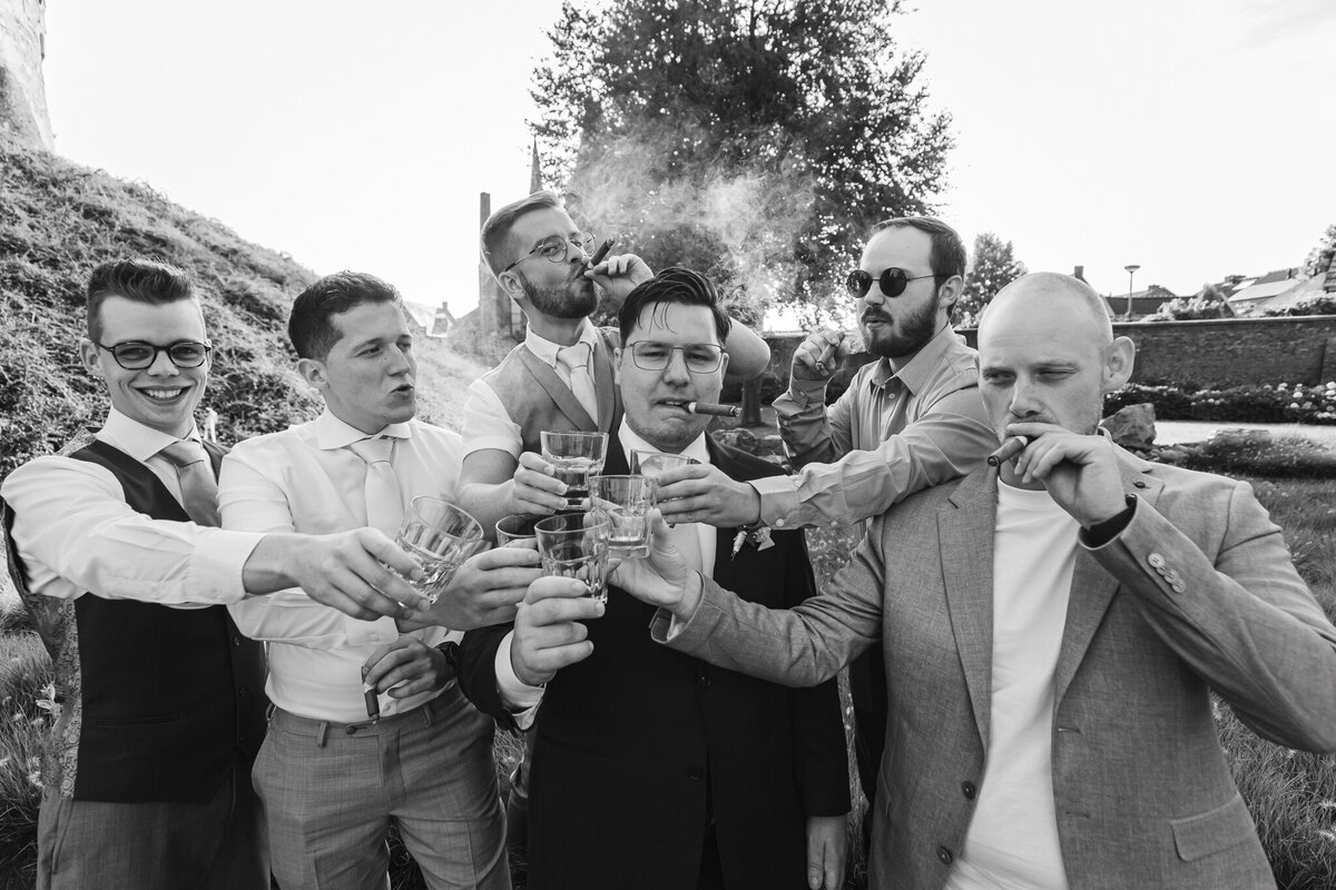 Vrolijke groepsfoto van bruiloftsgasten die toasten op de liefde tijdens de receptie.
