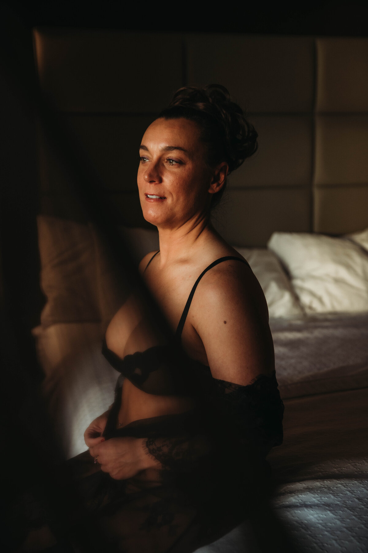 Pohoto of woman sitting in hotel room at sunset for boudoir.