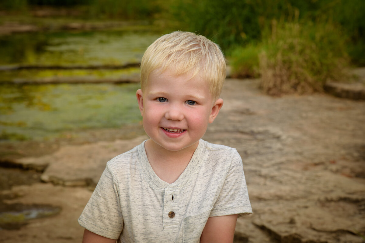 Portrait of little blonde haired boy smiling at the camera at Fonferek Glen County Park near Green Bay, Wisconsin