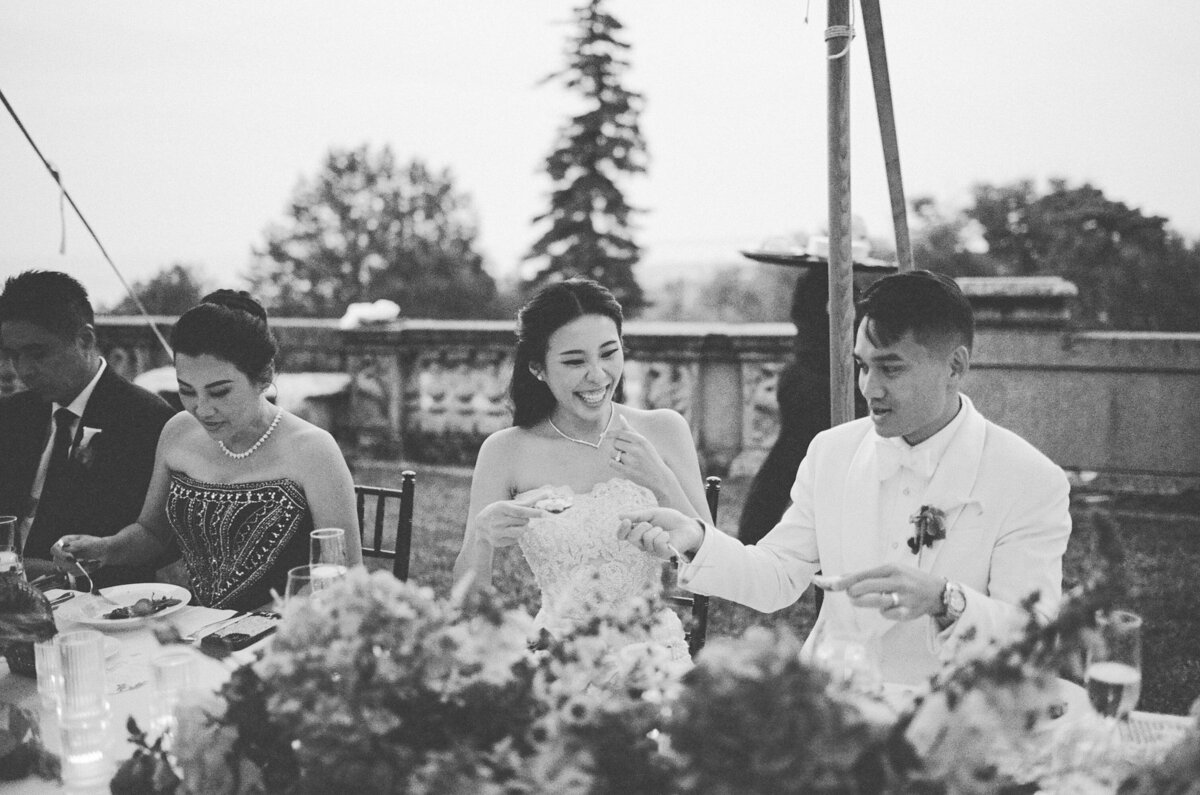 bride and groom laugh and share an oyster at reception at crane estate in ipswich taken by boston documentary wedding photographer