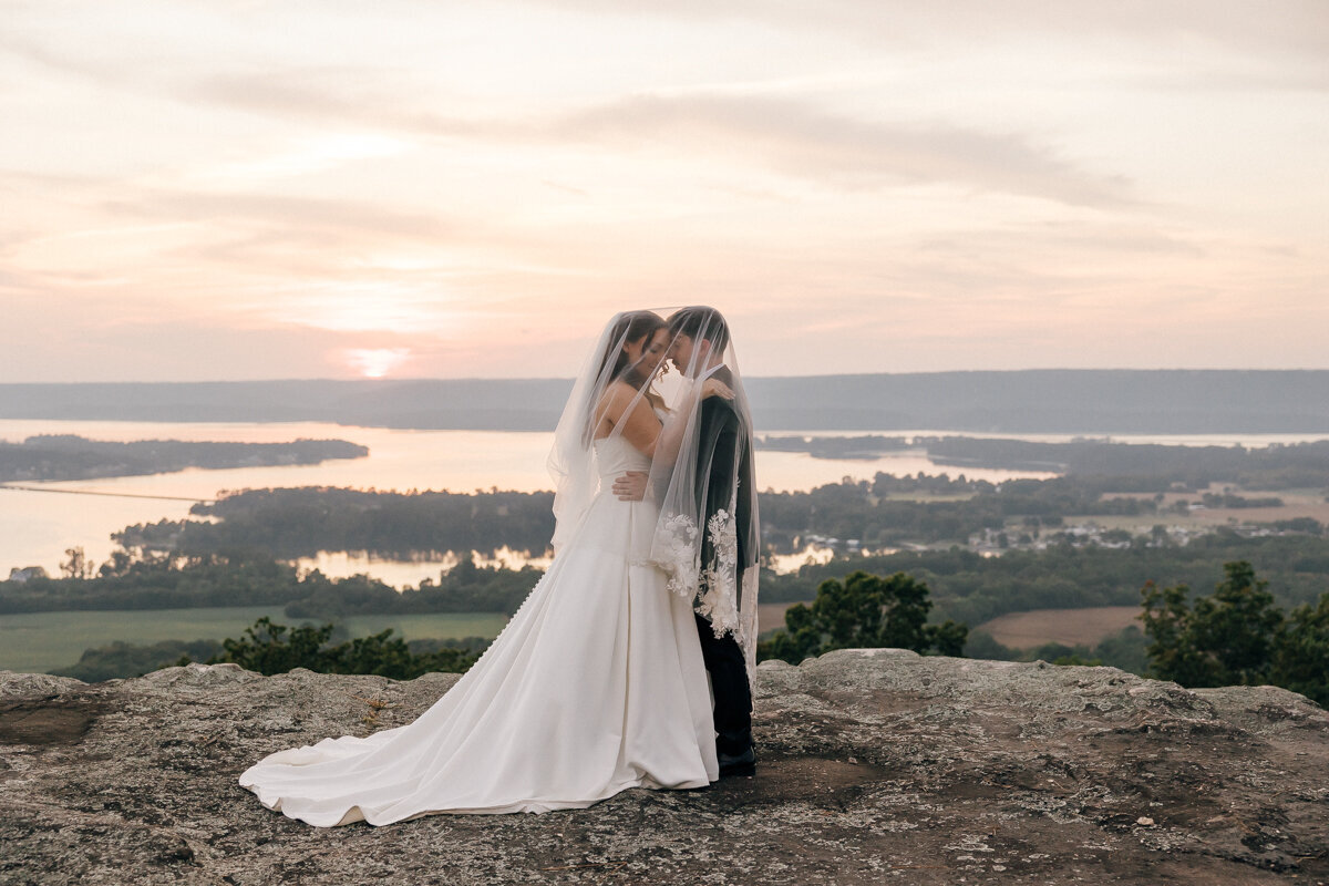 Newlyweds embracing with a beautiful mountaintop view in background at Stone Haven Wedding Venue.