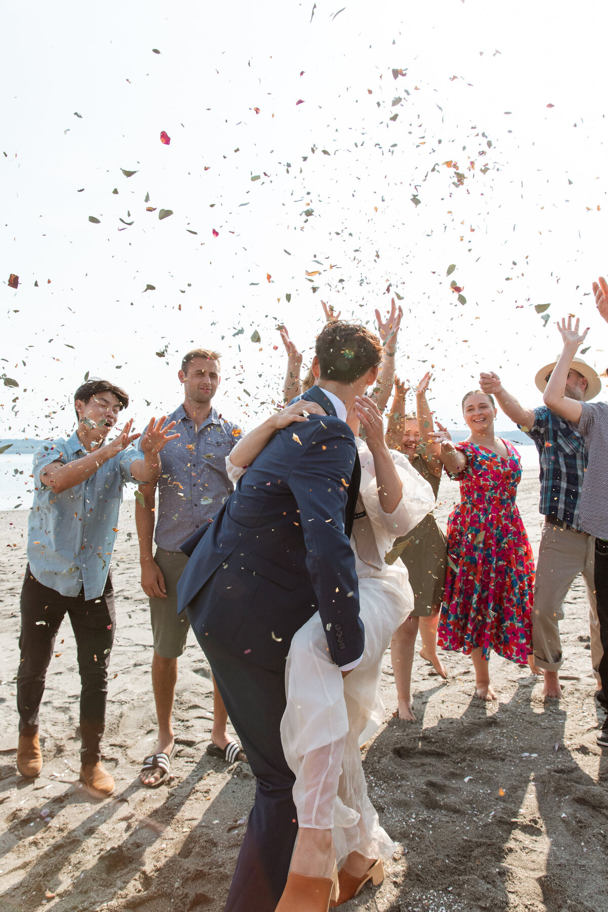 Guests throw confetti in the air after couple is married on the beach