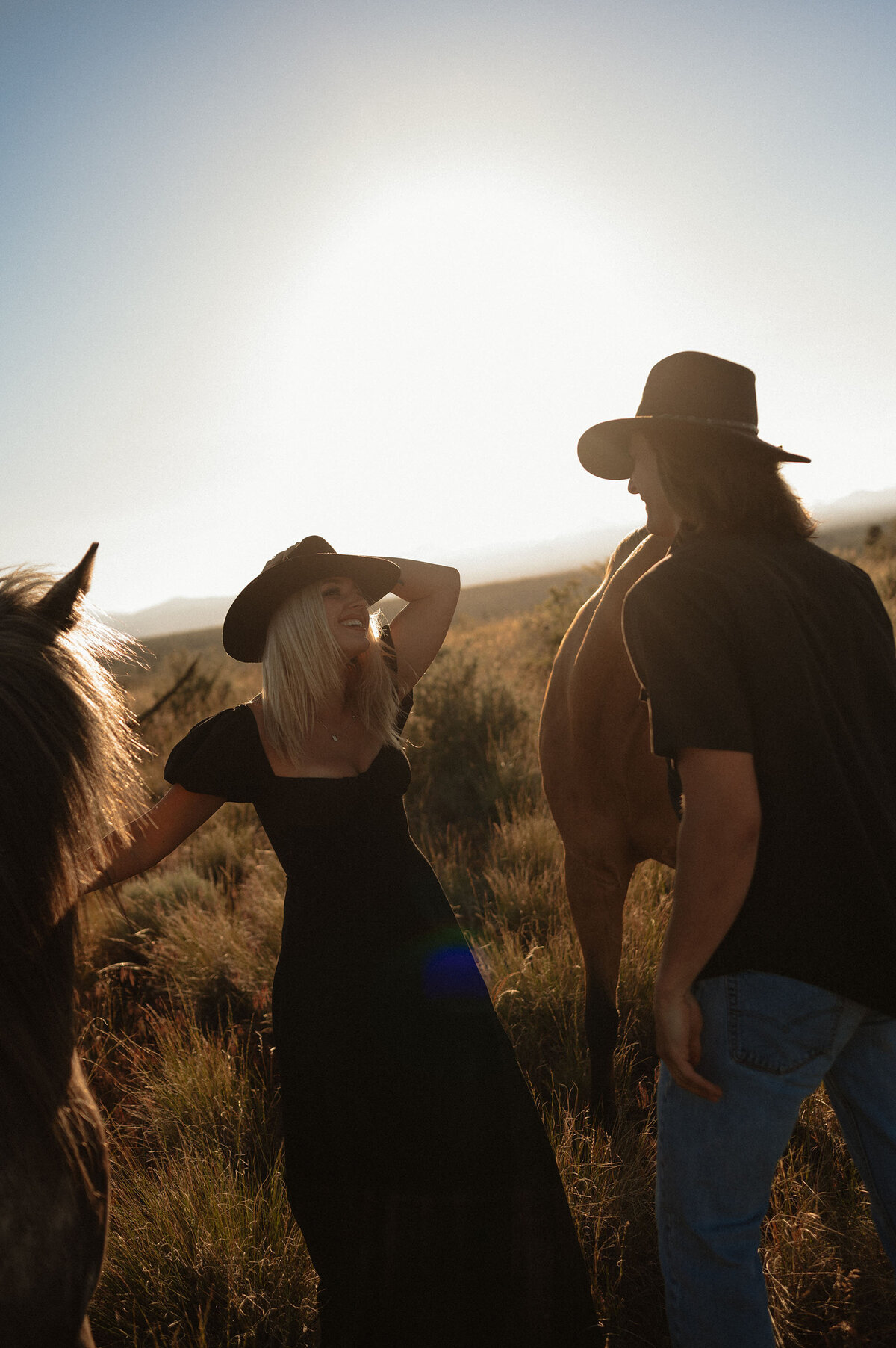 intimate sunset moment of couple with their horse, surrounded by warm light in the open outdoors