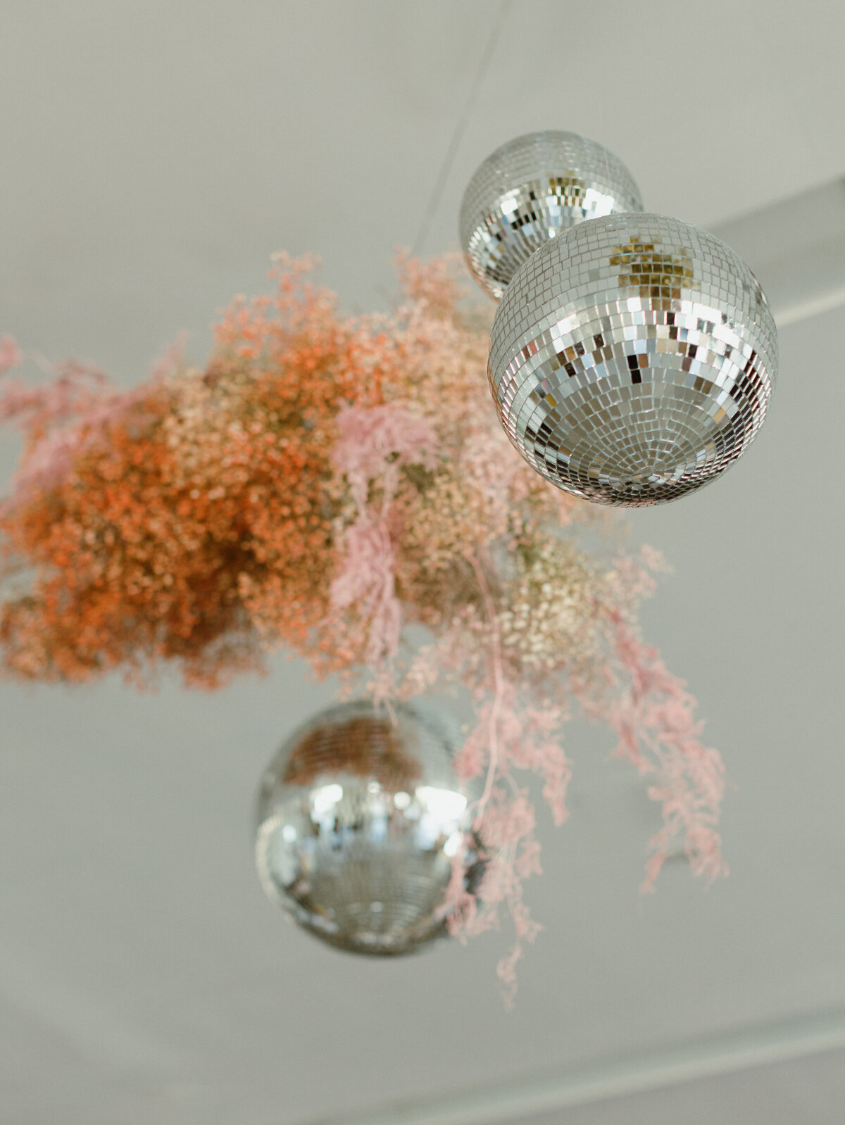 Hanging disco balls with pink baby’s breath installation, part of a custom Austin event floral design for weddings or branded corporate celebrations.