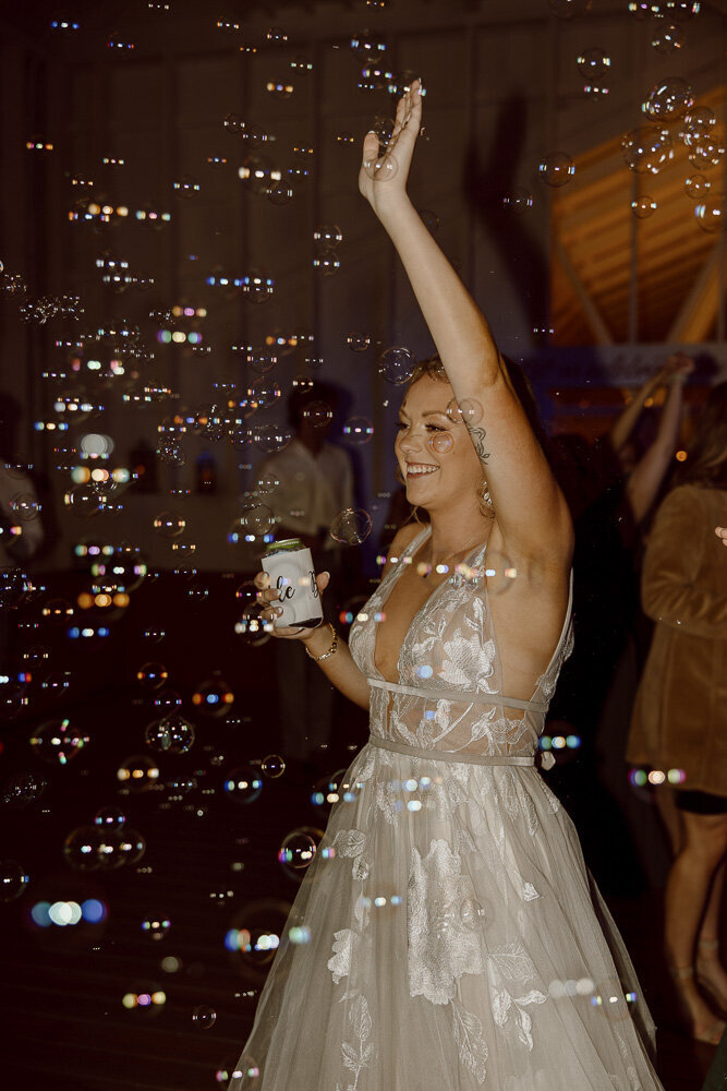 Bride dancing at wedding reception surrounded by bubbles