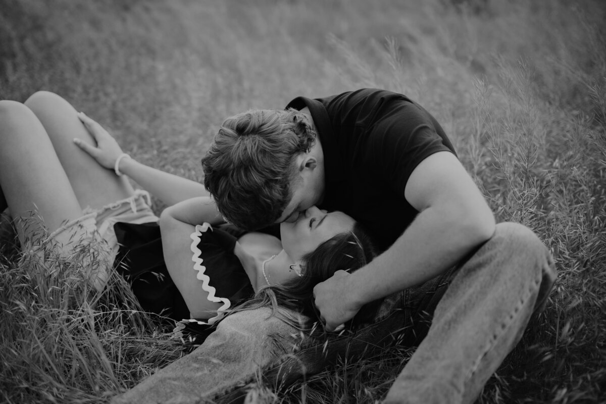 couple laying in grass kissing in black and white, couples portrait photography in amarillo