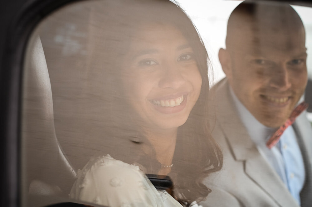 Brautpaar sitzt im Auto und lächelt in die Kamera