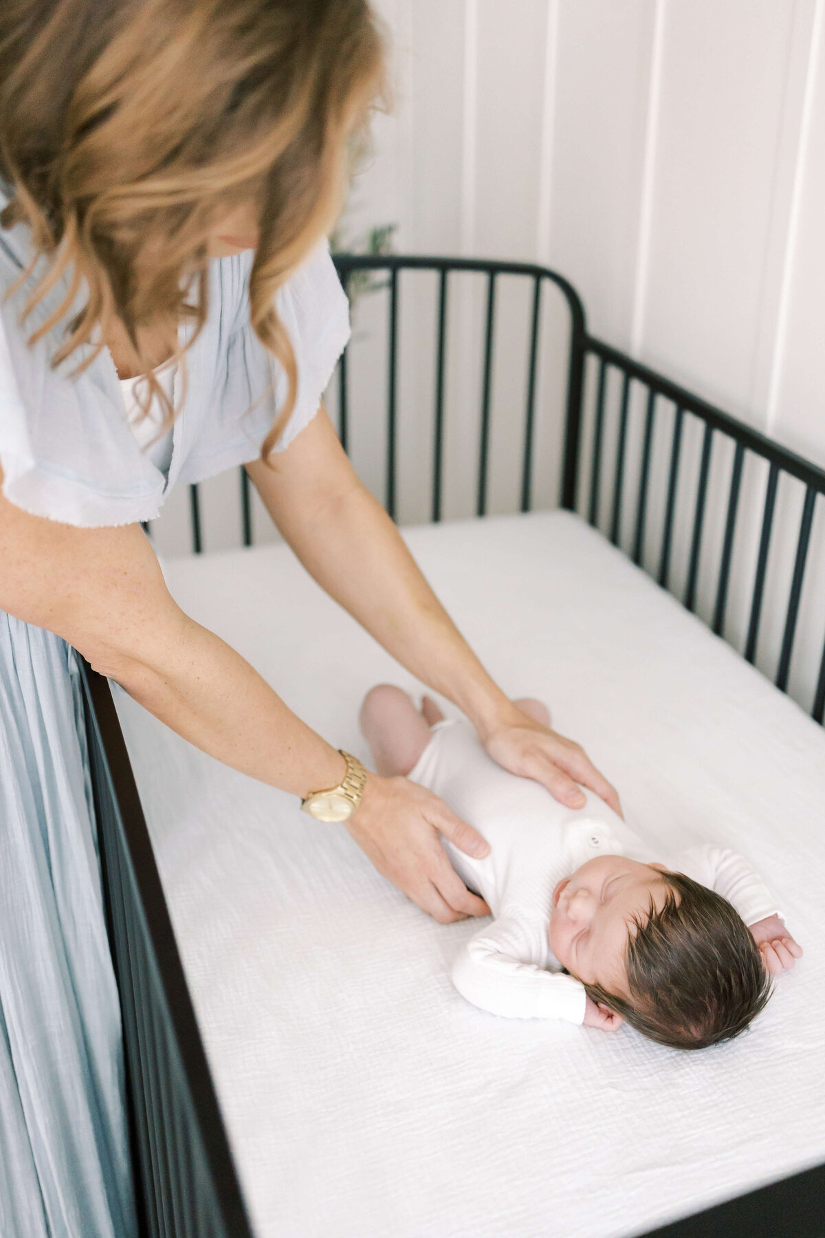 a mom putting her baby in their crib