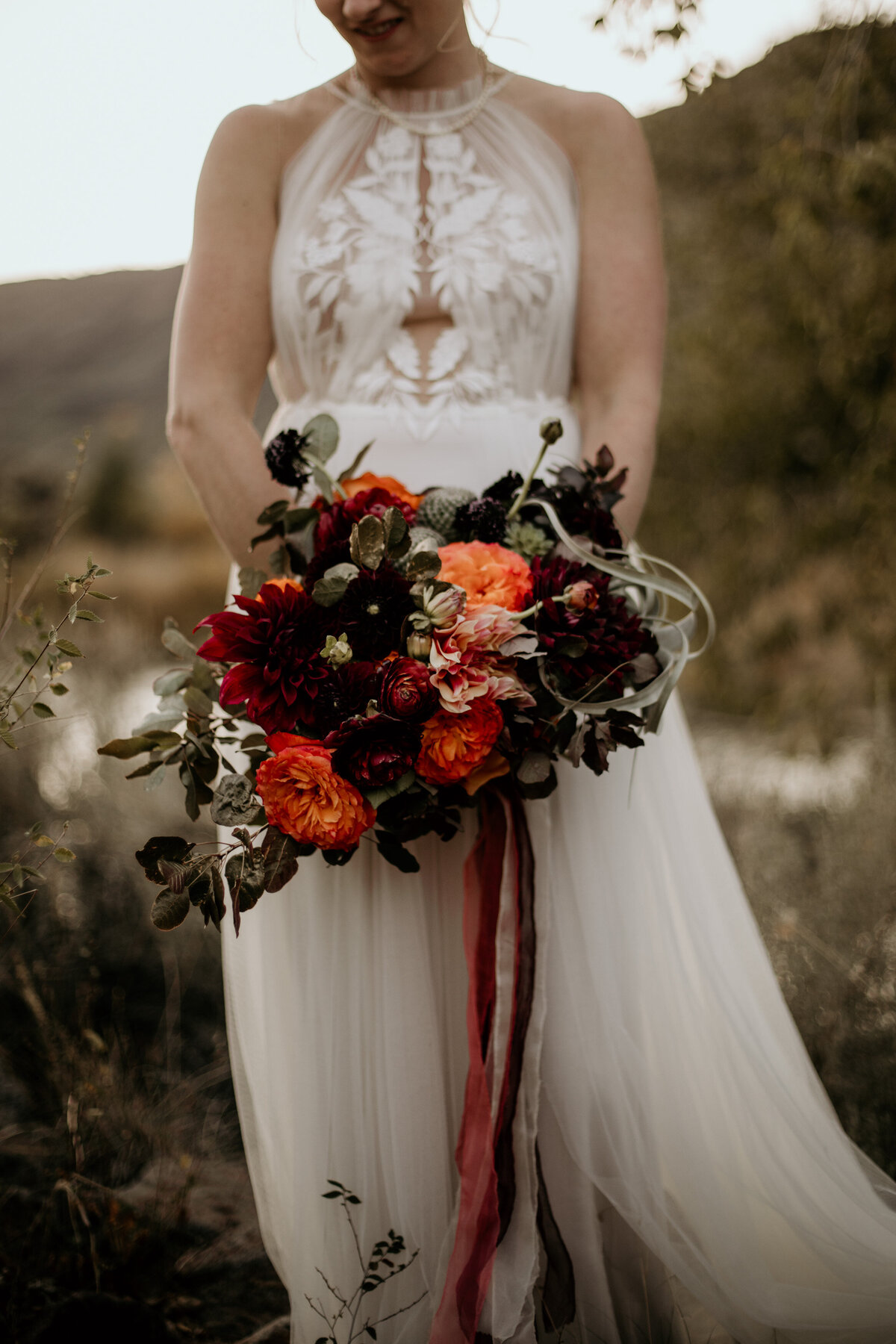 bride holing red and orange bouquet