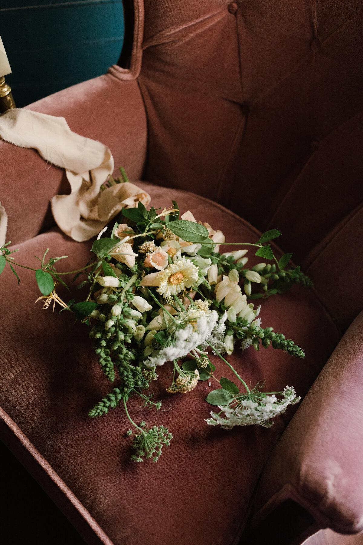 Wildflower bouquet lying on velvet pink chair at Mattie's Austin wedding