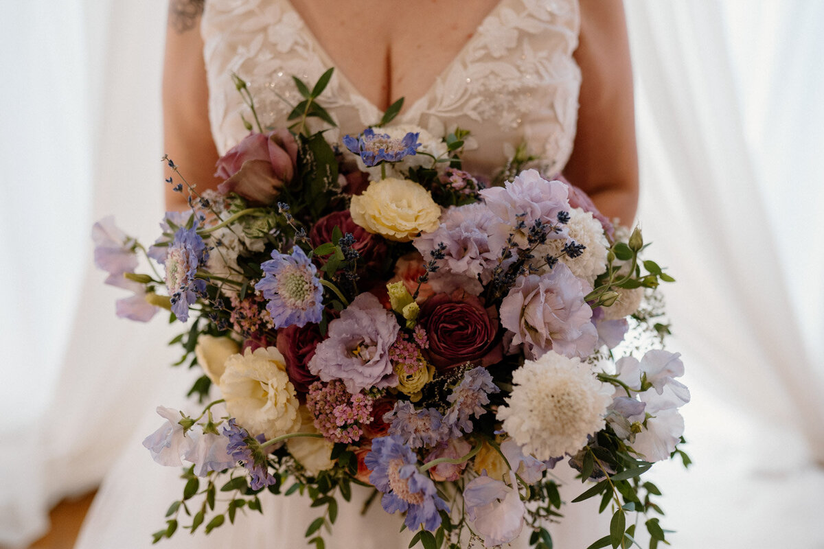 Bride holding bouquet of mixed pastel and deep blooms