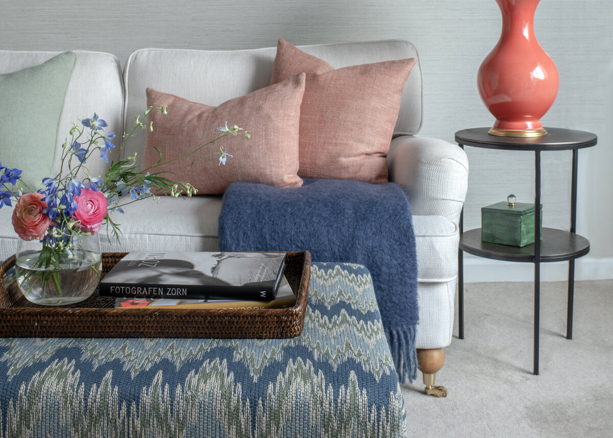 Soffa med rosa linnetextil, blå ullpläd och blomsterarrangemang – miljö från Caspar & Co:s showroom i Lidingö