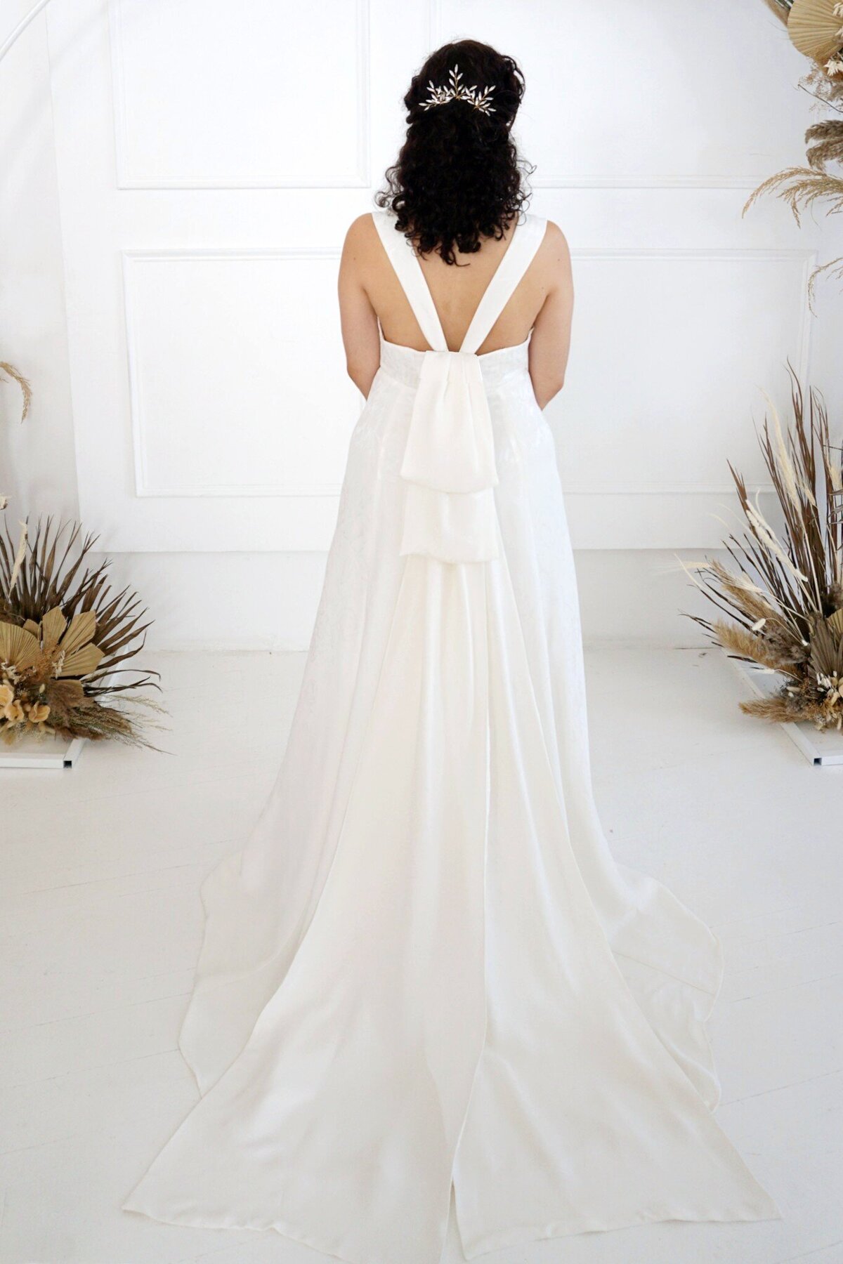 The back of the Sol modified a-line wedding dress features a detachable oversized bow that sits under the v-back.