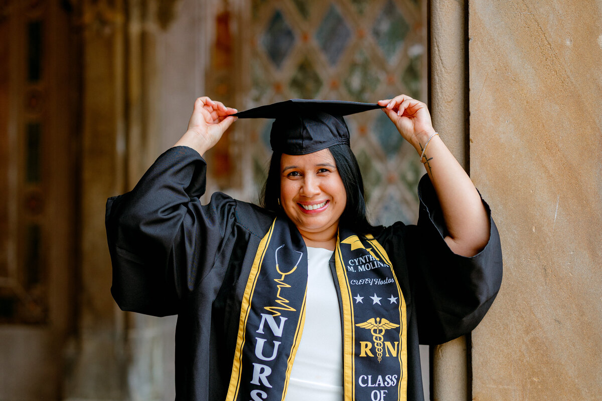 Hostos Community College nursing graduate smiling in cap and gown at Central Park.
