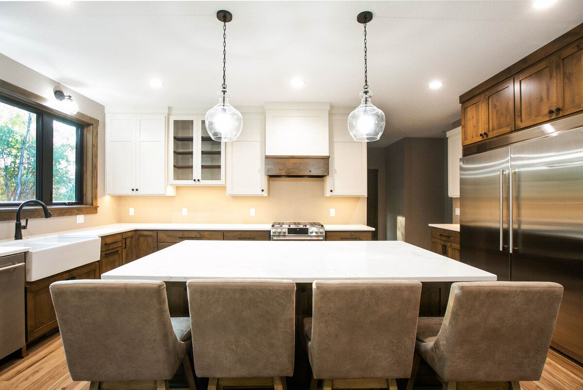 Open kitchen with dark cabinets, large island, and quartz countertops in an Big Lake Township custom home