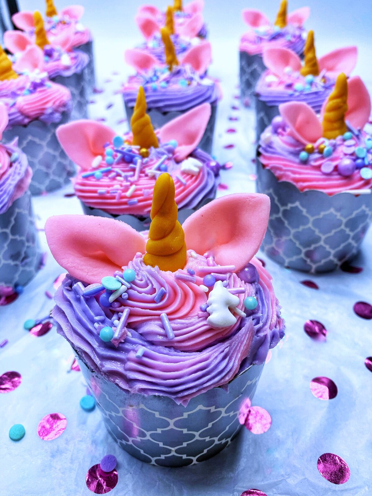 Purple and pink buttercream swirl cupcakes decorated with unicorn horn, ears, and sprinkles