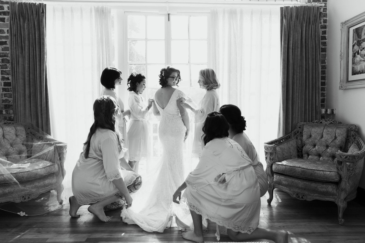 Bride being tended to by her bridesmaids, in black and white