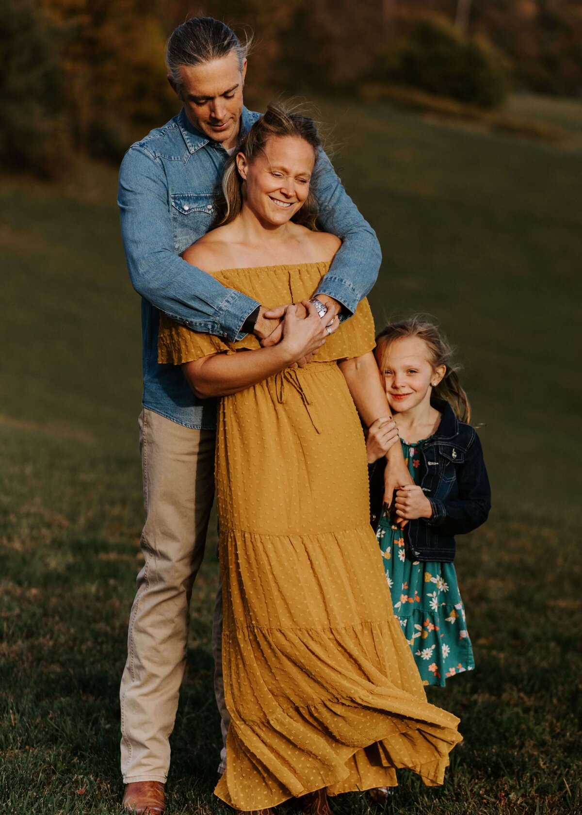 A family embracing in a field at sunset captured by a Pittsburgh family photographer.