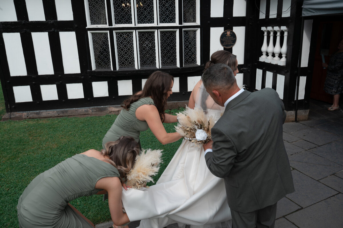 bridemaid and bride's dad helping her dress during candid moment - manchester wedding photography