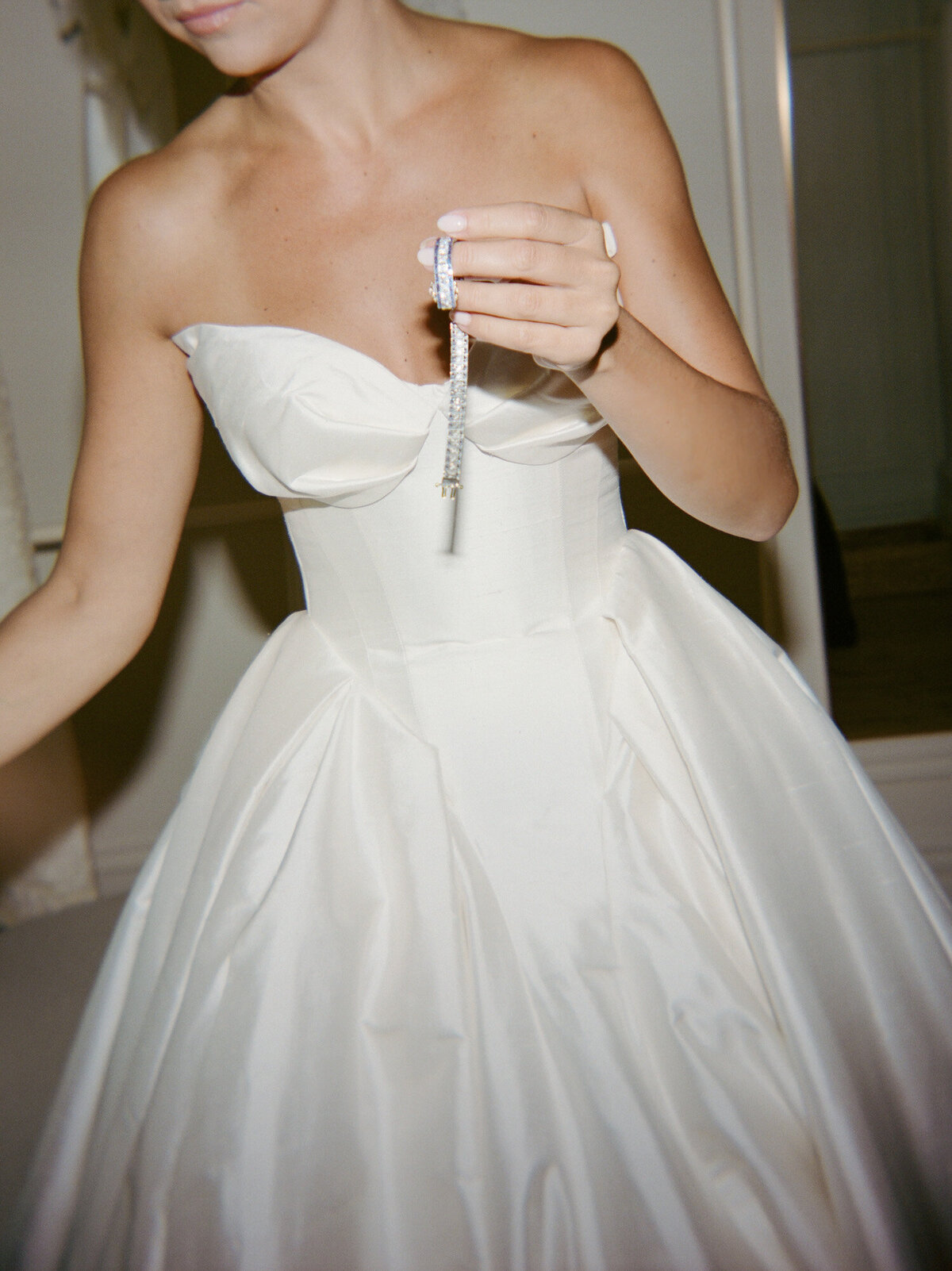 editorial film wedding photograph of a bride getting ready, holding an heirloom sapphire bracelet before placing it on her wrist