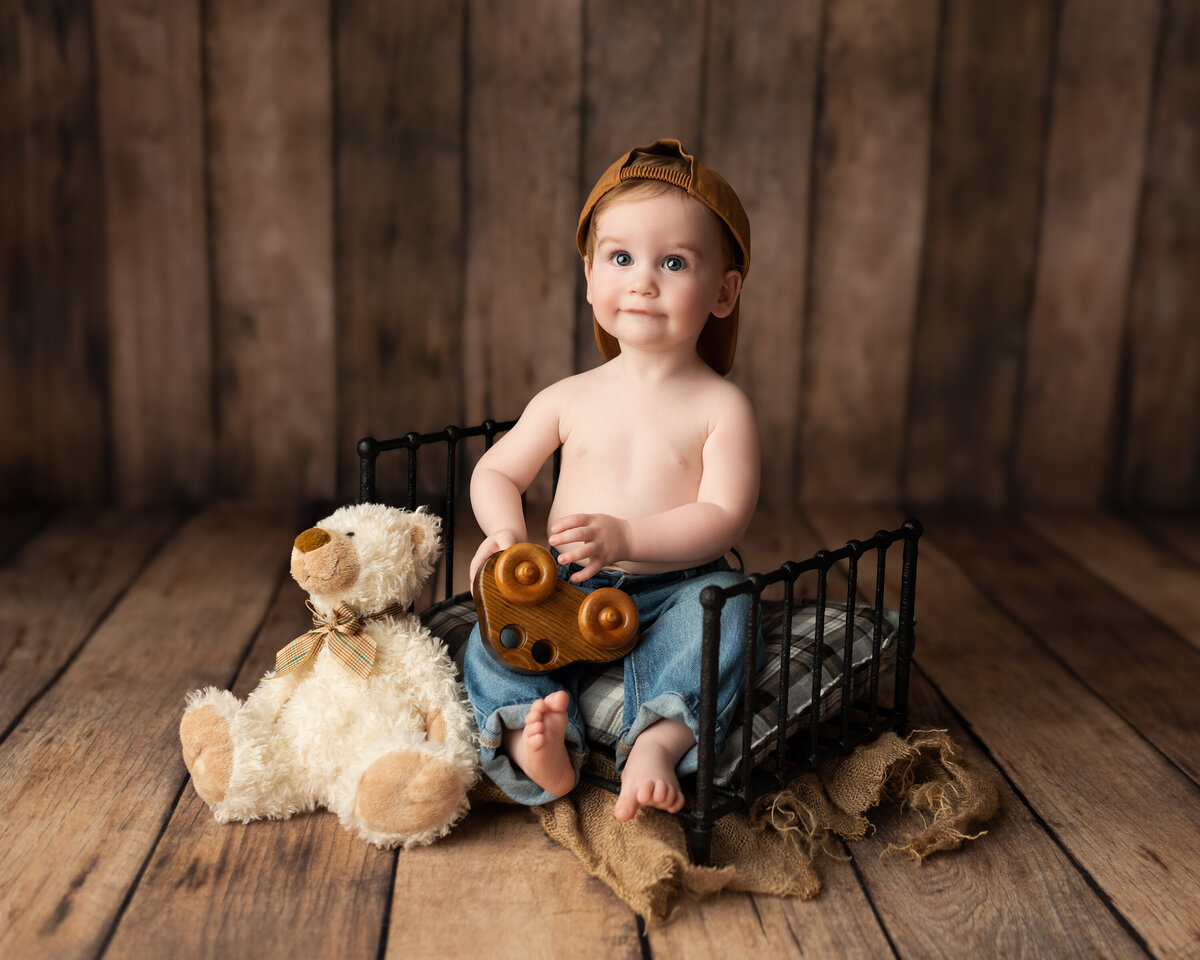 Rustic milestone photo of a baby boy with toy and teddy—styled with earthy tones and timeless textures.