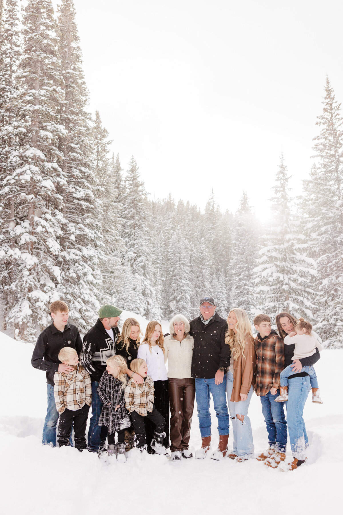 A large extended family stands together in snowy Vail mountains smiling for a Breckenridge Family Photographer