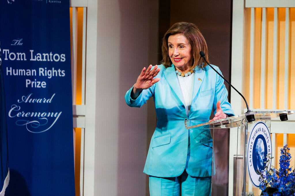 A woman in a blue suit waves at the audience.