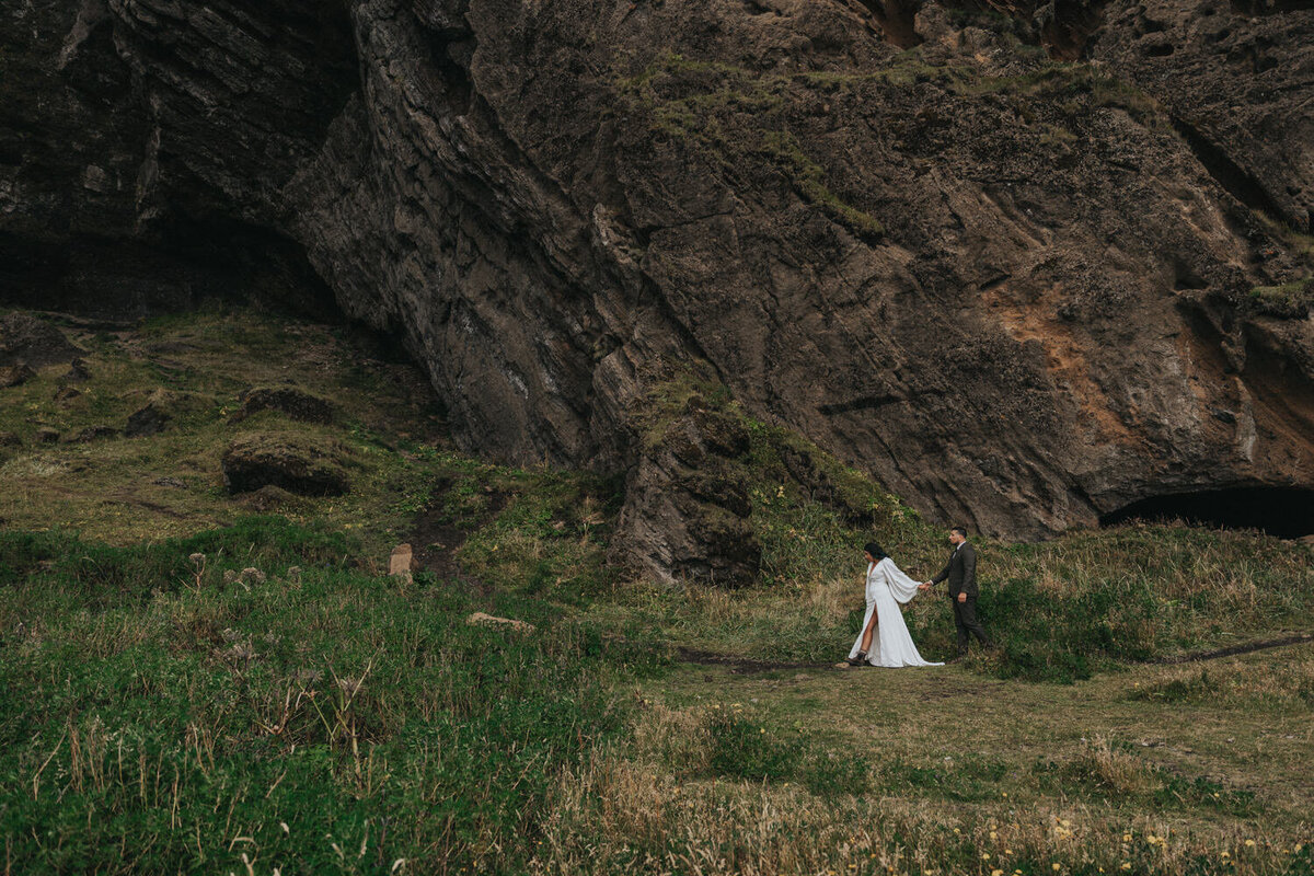 Husband and wife walk up a green Icelandic mountain 