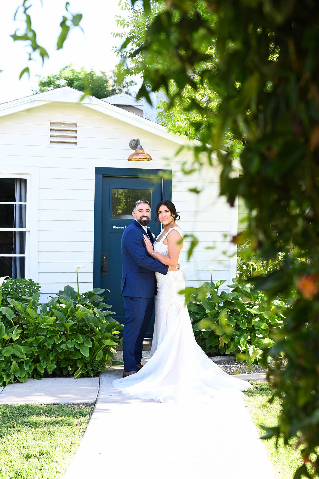 A bride and groom standing close together in front of a quaint house