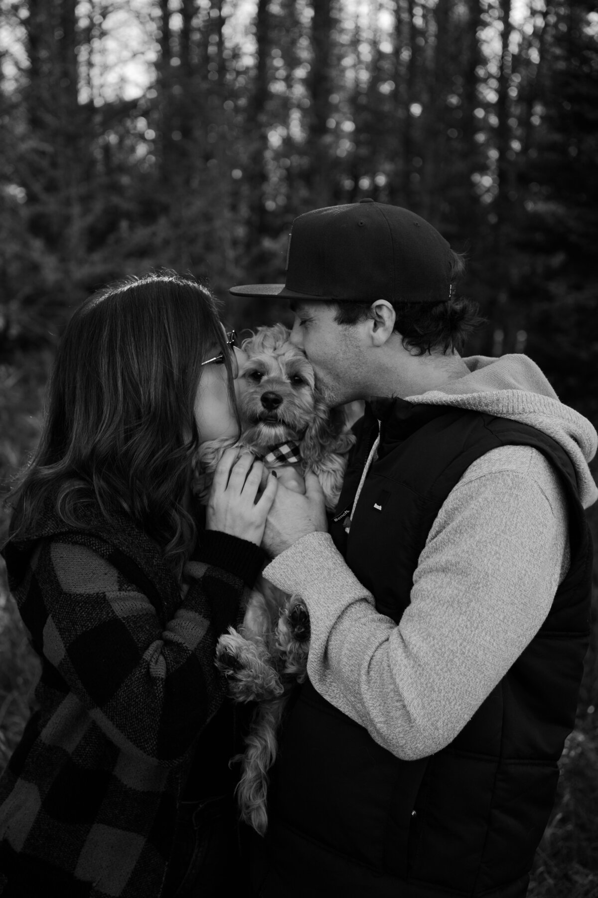 black and white image couple kissing dog